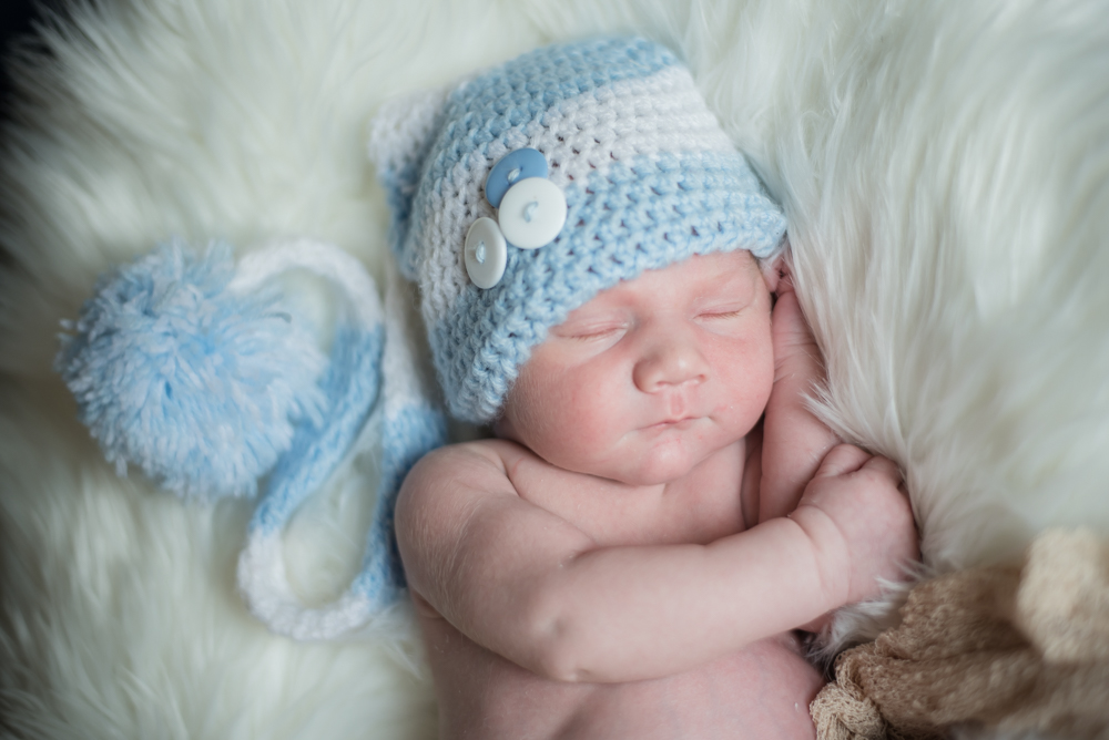 Cuddled up baby in hat, newborn portraits Cumbria