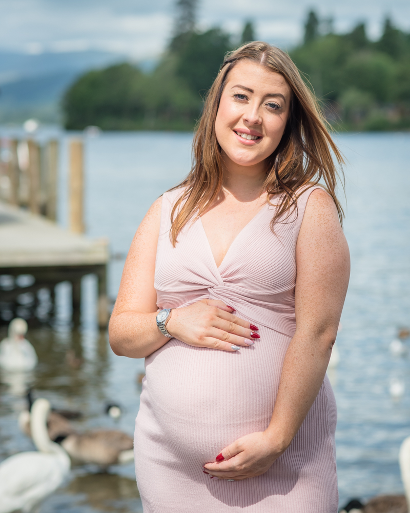 With the jetty and swans in background, maternity photographer Lake District